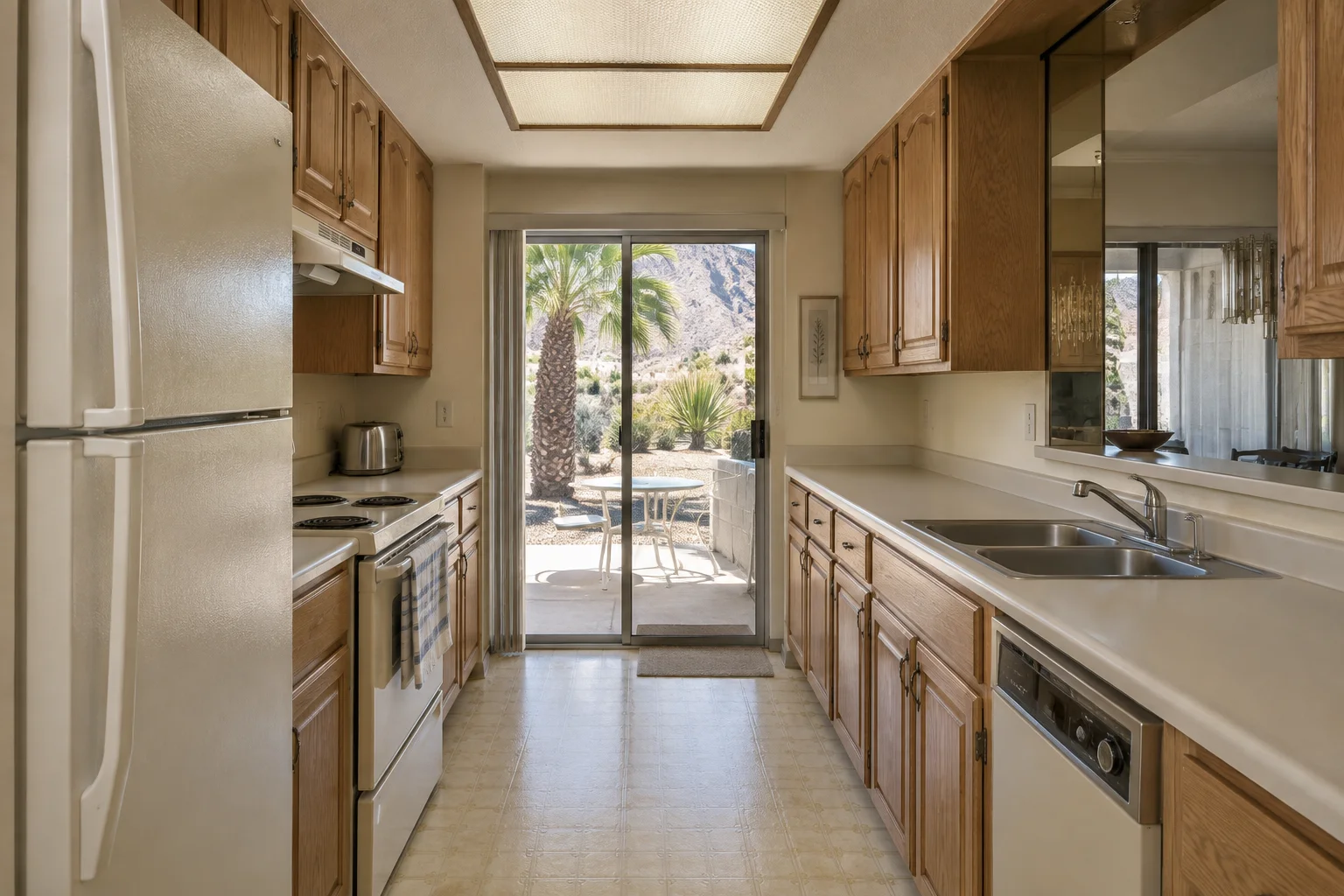 Narrow 1980s condo galley kitchen with oak raised panel cabinets, almond laminate counters and a fluorescent ceiling box